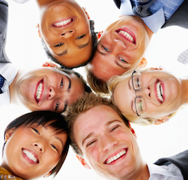 a group of people smiling and looking down in a circle